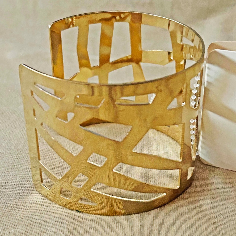 BRACELET, GOLD TONE METAL WITH CUT OUT DESIGNS, 7 ⅜ x 2 5/16 INCHES, TAG ON,